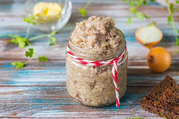Appetizer, herring, onion and boiled egg forshmak in a glass jar on a wooden background. Jewish cuisine. Fish recipes