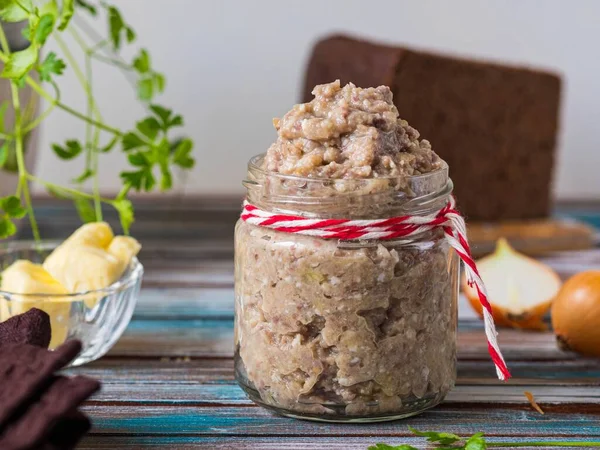 Appetizer, herring, onion and boiled egg forshmak in a glass jar on a wooden background. Jewish cuisine. Fish recipes