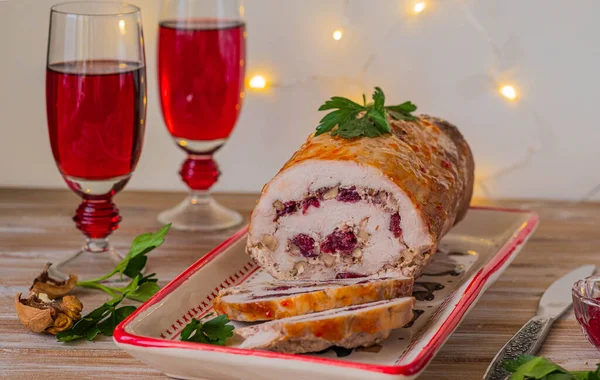 Cold appetizer or hot dish, pork roll with dried cranberries and walnuts on a clay dish on a light wooden background. Served with cranberry sauce. Festive dishes