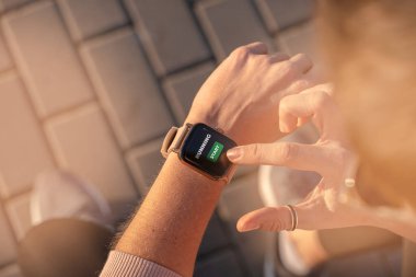 Formda bir kadın akıllı saati, giyilebilir teknolojiyi kontrol ediyor. Spor ayakkabısı spor koşusu, dışarıda yürüyüş. Sokakta koşu ayakkabıları ile yukarıdan görünüm.