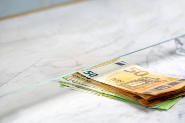 Bankanın vitrininde veznedara para ödeyen kişi, yakın plan. Almak ve satmak için 50 ve 100 avroluk banknotları takas edin..