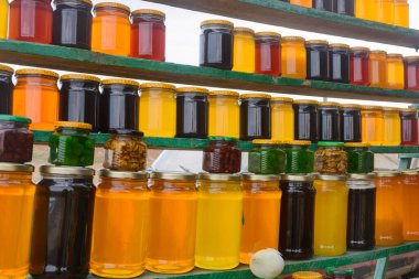 Kavanozda satılık bal var. Market tezgahında arıcılık ürünleri var. Yakın çekim, seçici odaklanma.