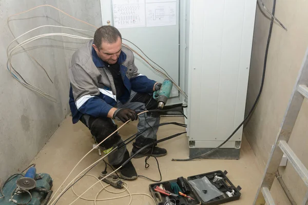 Connection of the electric cable to control cabinet using heat-shrinkable sleeve. Electrician man at work.