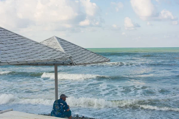 Adam plajda güneşlenir ve denizdeki fırtınaya bakar. Yüzmek yasaktır.