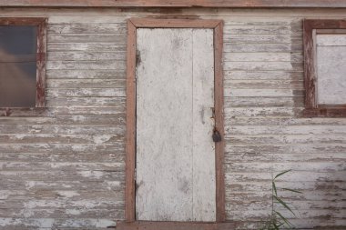 Pencereli terk edilmiş ahşap bina. Kapı demir bir asma kilitle kilitlenmiş..