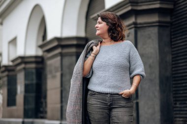 Eski bir sokakta ceketini tutan bir turist gülümsüyor. Arka plan bulanık. Boşluğu kopyala