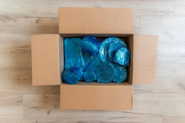 Skleněné zboží zabalené v modrém obalu nylonu na dně lepenkové krabice. Skleněné zboží zabalené v krabici — Stock fotografie