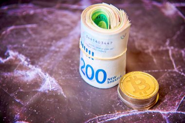 İsrail Shekel ILS banknotlarını kripto para jetonlarının yanına yuvarla Bitcoins 'in bozuk paralarını, yukarıdan, eski mermer tahtanın üzerine kes. Seçici odaklanma. Metin yerleştirme için boşluk ile. 