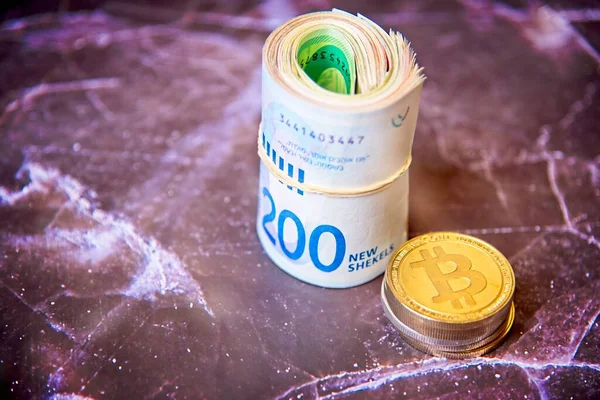 Roll Israeli Shekel ILS banknotes near cryptocurrency tokens Bitcoins bit coins, saw from above, on old marble board. Selective focus. with space for text placement. —  Fotos de Stock