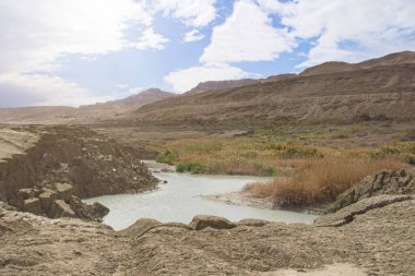 Ölü Deniz kıyısı yakınlarında, turkuaz suyla dolu bir subatan. Deniz seviyesindeki düşüşün devam etmesi nedeniyle tatlı su girmesiyle yeraltı tuzu çözüldüğünde delik oluştu.. 