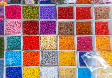 Boncuklar renklerine göre sıralanır. Kutulardaki renkli parlak boncukların arkaplanı, dikiş için ayarlandı.