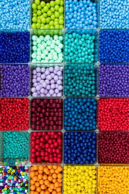 Boncuklar renklerine göre sıralanır. Kutulardaki renkli parlak boncukların arkaplanı, dikiş için ayarlandı.