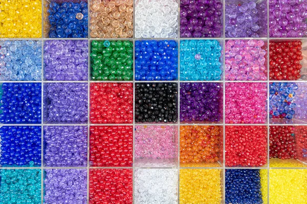 Koraliki są ułożone i posortowane według koloru. Tło kolorowych jasnych koralików w pudełkach, zestaw do robótek ręcznych. — Zdjęcie stockowe