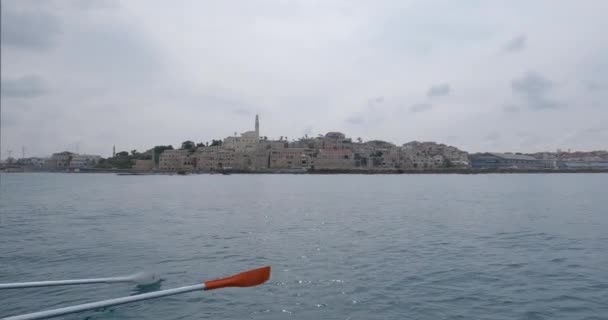 A view from the waterfront of the Jaffa old town architecture buildings. A rowboat sailed in front of a harbor of the port of Old Jaffa. — Vídeos de Stock