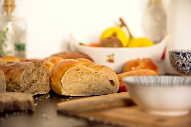 Ziyafet, dağınık masa. Saç örgüsü şeklinde bir ekmek. Tatlı Challah. Kahvaltı, yan görüş. Kiraz domatesleri ve zeytinyağı, Balzamik sirke, Atlantik tuzu ve meyveler 