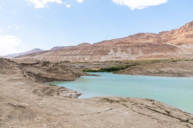 Ölü Deniz kıyısı yakınlarında, turkuaz suyla dolu bir subatan. Deniz seviyesindeki düşüşün devam etmesi nedeniyle tatlı su girmesiyle yeraltı tuzu çözüldüğünde delik oluştu.. 