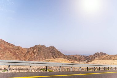 Dağlık bir çöl manzarasının yanında bir yol. Eilat, İsrail 'e giden 12. yolda, Mısır sınırında. Dağlar farklı ve değişik kum renklerinde. Yüksek kalite fotoğraf