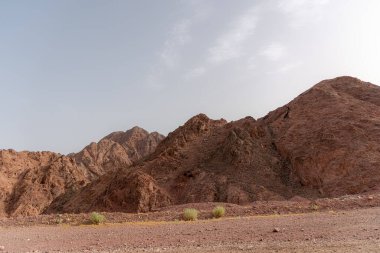 Dağlık bir çöl manzarasının yanında bir yol. Eilat, İsrail 'e giden 12. yolda, Mısır sınırında. Dağlar farklı ve değişik kum renklerinde. Yüksek kalite fotoğraf
