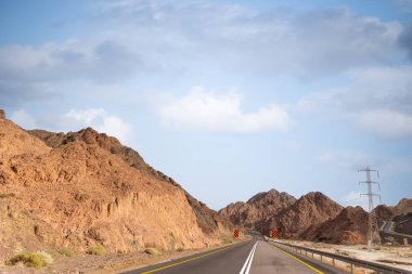 Dağlık bir çöl manzarasının yanında bir yol. Eilat, İsrail 'e giden 12. yolda, Mısır sınırında. Dağlar farklı ve değişik kum renklerinde. Yüksek kalite fotoğraf