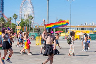 TEL AVIV ISRAEL HAZİRAN 2022: Deri etekli ve yüzünde köpek maskesi olan bir adam gurur bayrağını sallıyor. 