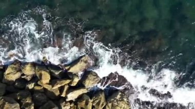 Aerial straight down view of the gorgeous and rugged Old Jaffa coastline. The camera moves steadily along the rocky bluffs ending in a magnificent swirl of ocean and rocks. 4k footage