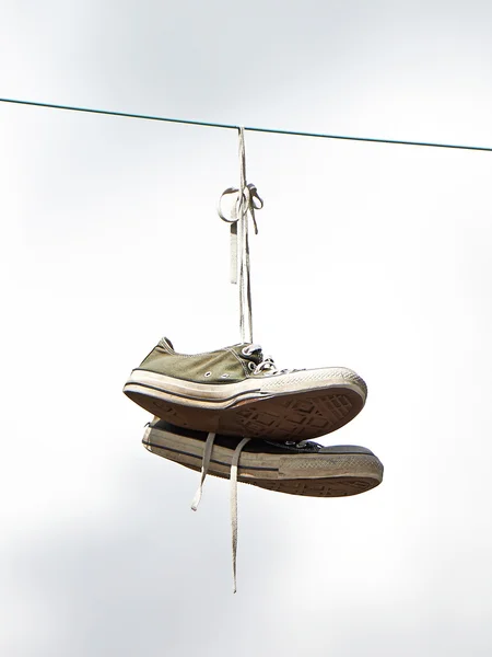 Old sneakers hanging from a powerwire — Stock Photo, Image