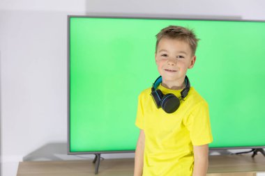 Dans eden küçük çocuk. Kulaklıklı çocuk TV karşısında dans edip şarkı söylüyor.