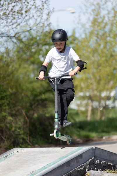 Der Junge Springt Auf Einen Roller lizenzfreie Stockfotos