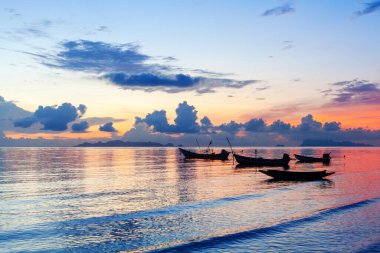 Güzel deniz batımı, okyanus gün doğumu, tropikal ada sahili, mavi su dalgaları, balıkçı teknesi, gemi silueti, renkli kırmızı turuncu gökyüzü, mor bulutlar, yaz tatili, tatil, seyahat