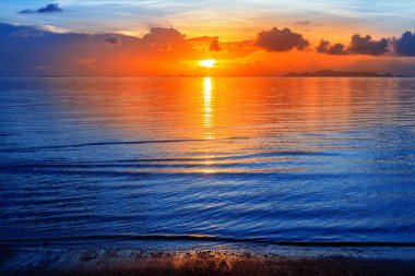 Renkli deniz batımı manzarası, parlak okyanus gündoğumu, sarı altın güneş yansıması, mavi su dalgaları, kırmızı turuncu gökyüzü, bulut, güzel tropikal ada manzarası, yaz tatilleri, tatil, seyahat