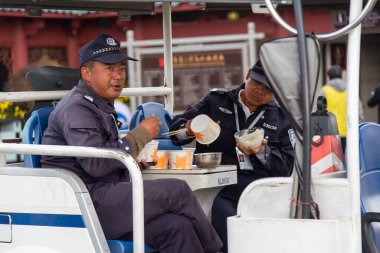 DALI, ÇİN. Şubat 2019. Güvenlik görevlileri yemeklerini araçta yiyorlar.