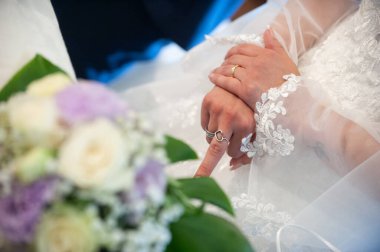 July 2022, Italy. Hands of a bride make the middle finger, during the wedding ceremony
