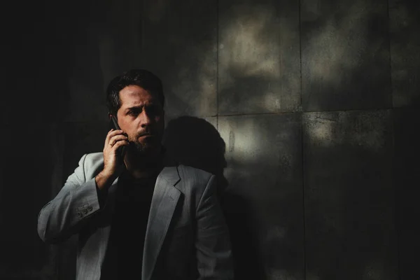 Mütevazı bir yönetici cep telefonuyla konuşuyor ve sağa bakıyor.