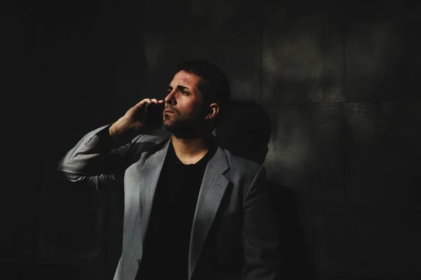 Alçakgönüllü bir yönetici cep telefonuyla konuşuyor ve sola bakıyor.