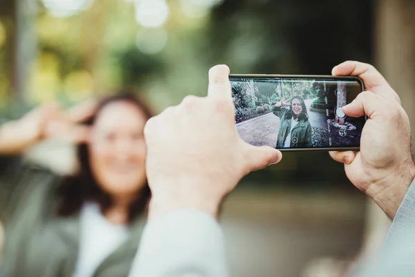 Селективное фокусирование на экране мобильного телефона, держащегося за руки, фотографирующего улыбающуюся девушку — стоковое фото