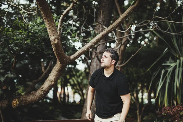 Yeşil bir parkta sabırsız bir tavırla duran bir adam.