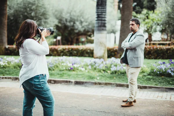 Parktaki bir iş adamının refleks kamerasıyla fotoğraf çeken bir kadın.