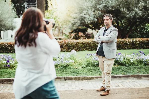 Parkta refleks kamerasıyla fotoğraf çeken bir kadın tarafından fotoğraflanan bir iş adamına odaklanın.