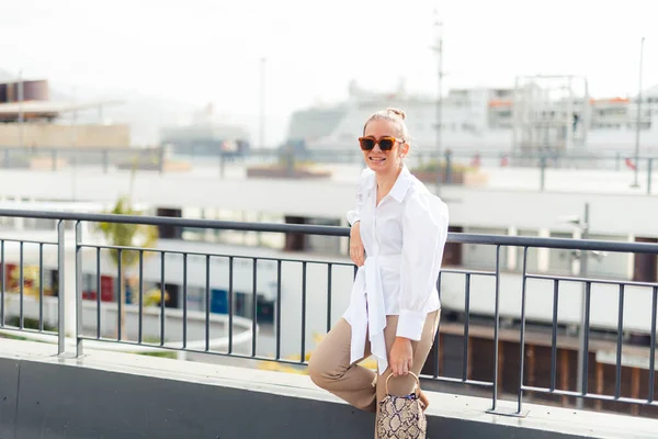 Güneşli bir günde şehrin korkuluklarına yaslanan bir kadın..