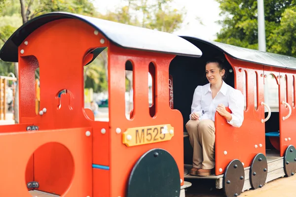 Parktaki oyuncak trende oturan bir kadın.