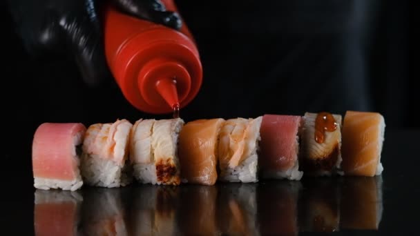 Professional sushi preparation. Sushi chef pours sauce on fresh rolls. — Stock Video