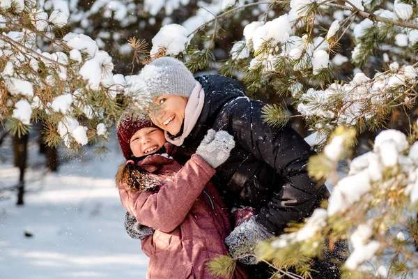Family winter walk in the forest. Raising a child, family habits. Mother and daughter are having fun in winter in the forest in sunny frosty weather. A mothers hug. — Stock Photo, Image