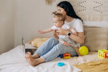 Evde çalışan serbest çalışan bir kadın. Çocuk annesinin internette dizüstü bilgisayarda çalışmasını engelliyor. Uzaktan kumanda. İnternette çalışıyorum. Bebek, annenin evde çalışmasına izin vermiyor..
