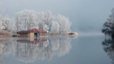 Sonbahar sabahı manzarası. Sis içinde gölün üzerinde gün doğumu. Kışın başlangıcında, ağaçların ve çimlerin üzerindeki yumurtayı. Nadir görülen bir doğa olayı - sis, don ve gün doğumu.