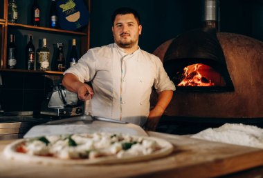 Şef ahşap fırında pizza hazırlar. Pizza pişiriyorum. Aşçı pizzayı fırına koyar..