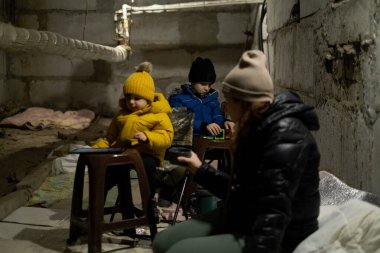 Rusya 'nın Ukrayna ile savaşı. Anne ve çocuklar sığınakta oturuyorlar. Ukrayna 'nın huzurlu şehirlerine ateş açın. Harkiv Bombalanıyor.