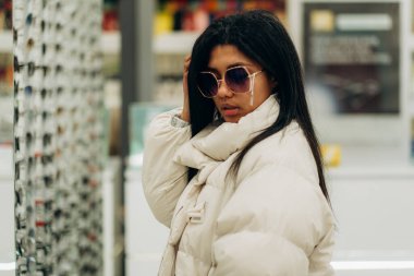 Genç bir Afrikalı Amerikalı kadın optik mağazasından gözlük seçiyor..