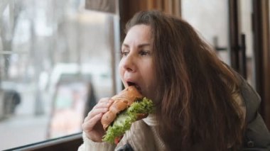 Genç bir kadın bir kafede oturur ve aromatik kahve içer..