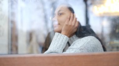 Genç bir Afrikalı Amerikalı kadın bir kafede oturur ve aromatik kahve içer..