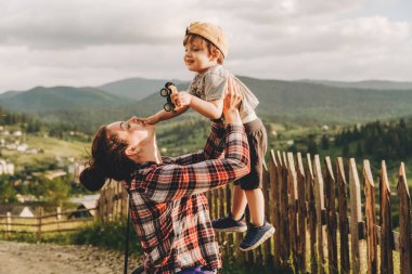 Bir anne gün batımında küçük oğlunu kollarına alır, bir dağın tepesinde durur. Yaz akşamları dağın tepesinden gelen dağ manzarası..